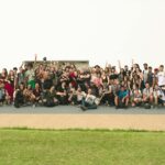 A joyful group of diverse friends celebrating outdoors on a sunny day.