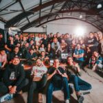 A happy and diverse group posing together in a São Paulo warehouse setting.