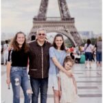 A happy family posing in front of the iconic Eiffel Tower in Paris, France.